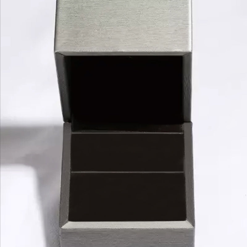 Open silver jewelry box with a soft black interior, perfect for storing rings or other jewelry.