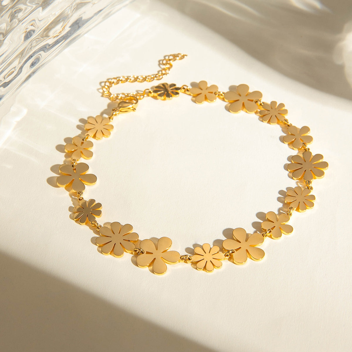 18K gold-plated flower bracelet displaying a delicate design with multiple floral charms, set against a bright background.